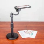 Black plastic phone holder on a three-legged desktop phone tripod standing on a table