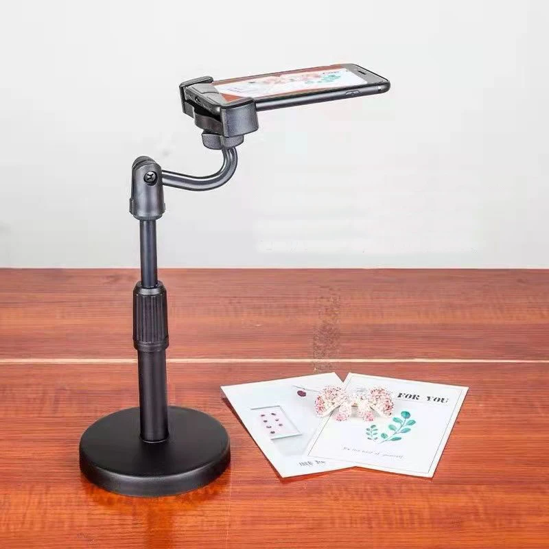 Black plastic phone holder on a three-legged desktop phone tripod standing on a table