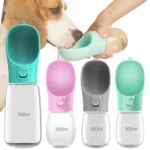White portable dog water bottle with spout held beside a walking dog